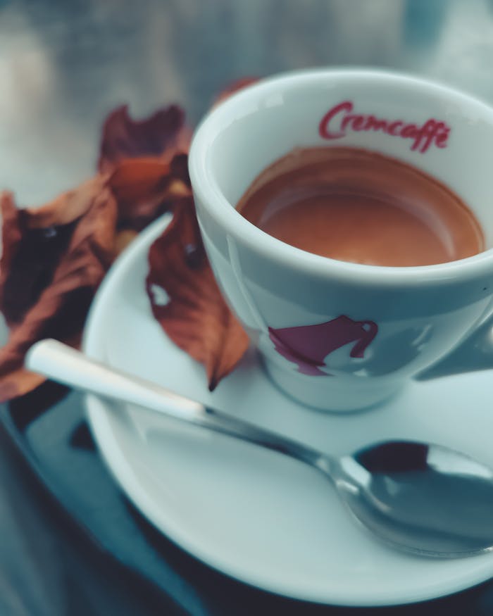 Warm espresso served in a ceramic cup with autumn leaves on the saucer.